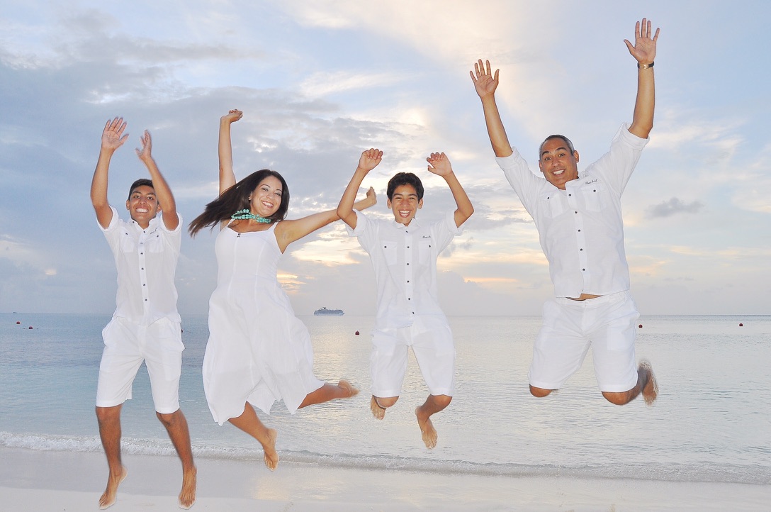 Garza family jumping on the beach in white at sunset