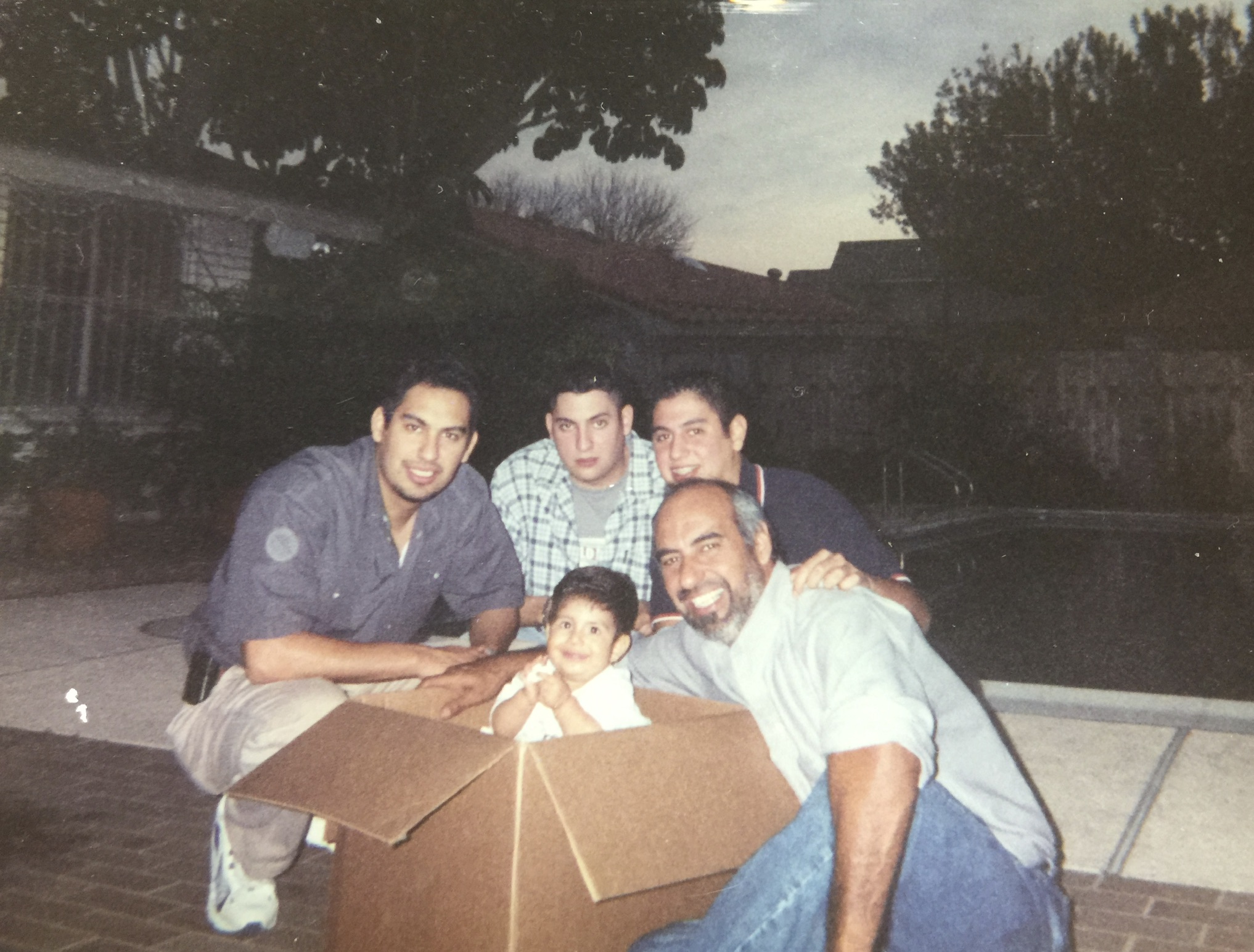 Vintage backyard photo of father and brothers with baby A. Jimmy Garza III
